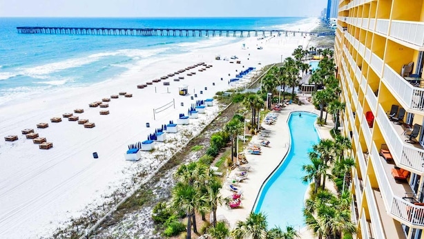 Un hotel con piscina, playa y muelle.