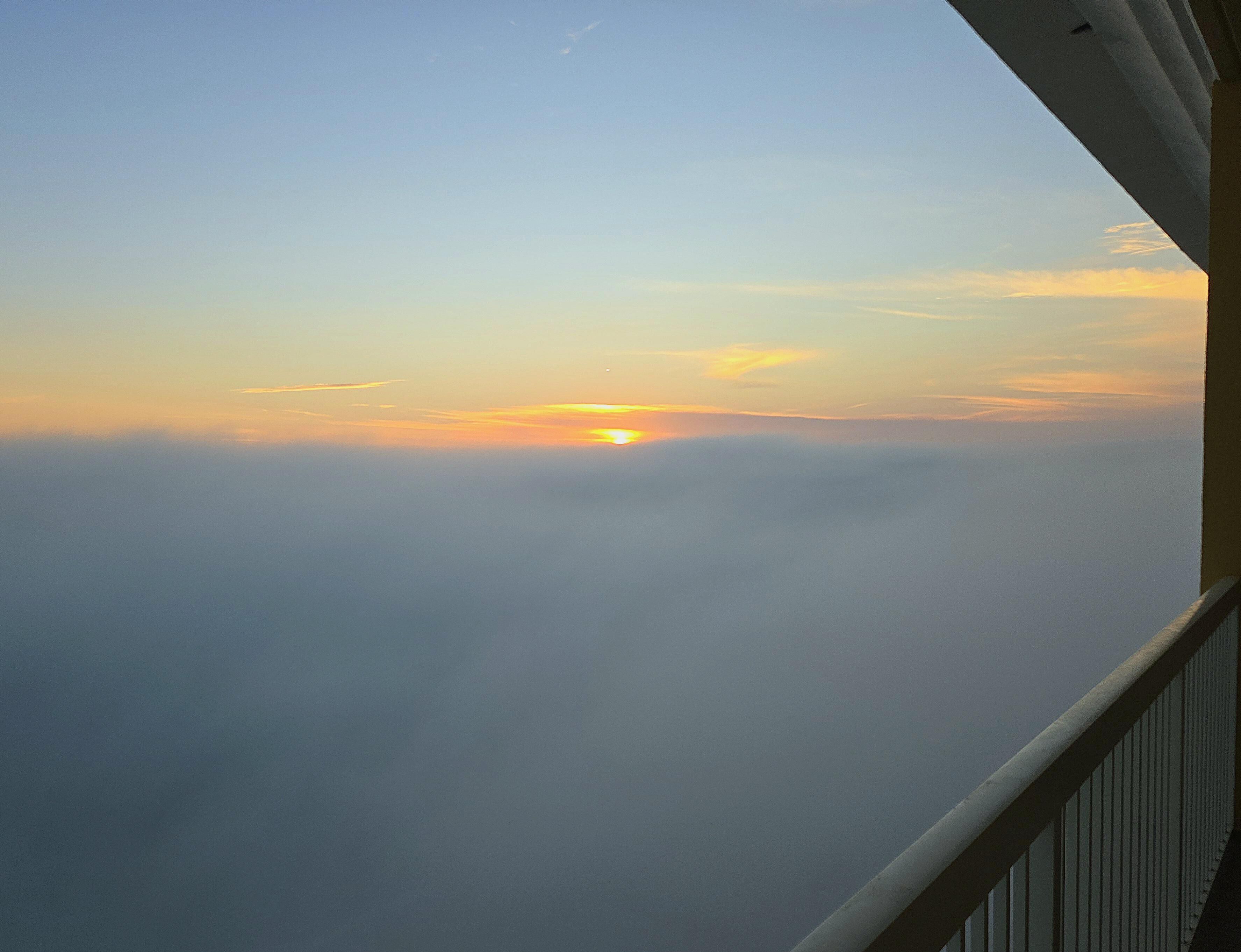 A sunrise over a cloud-covered landscape viewed from an elevated position.