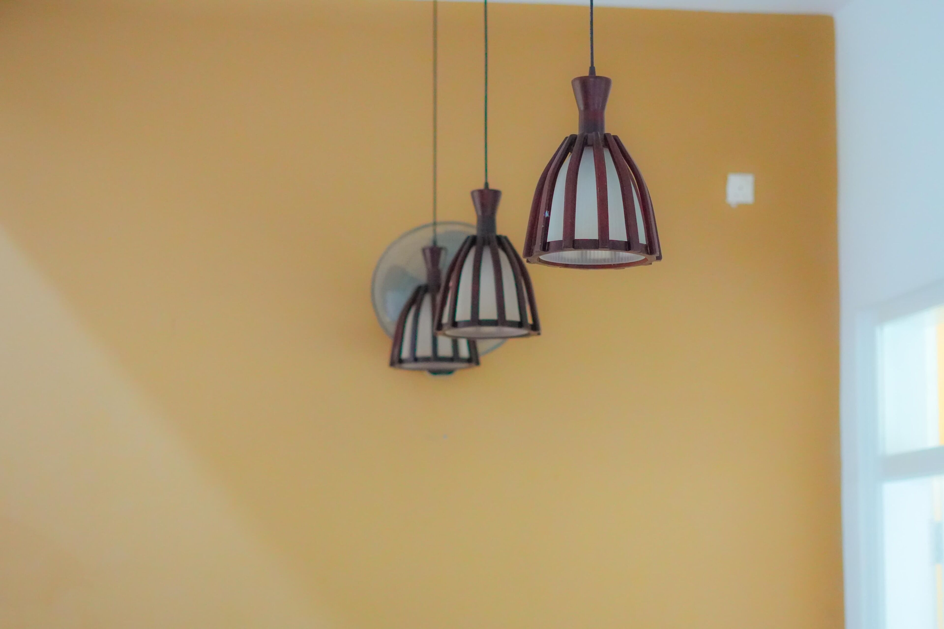Three pendant lights hanging from the ceiling in a room with yellow walls.