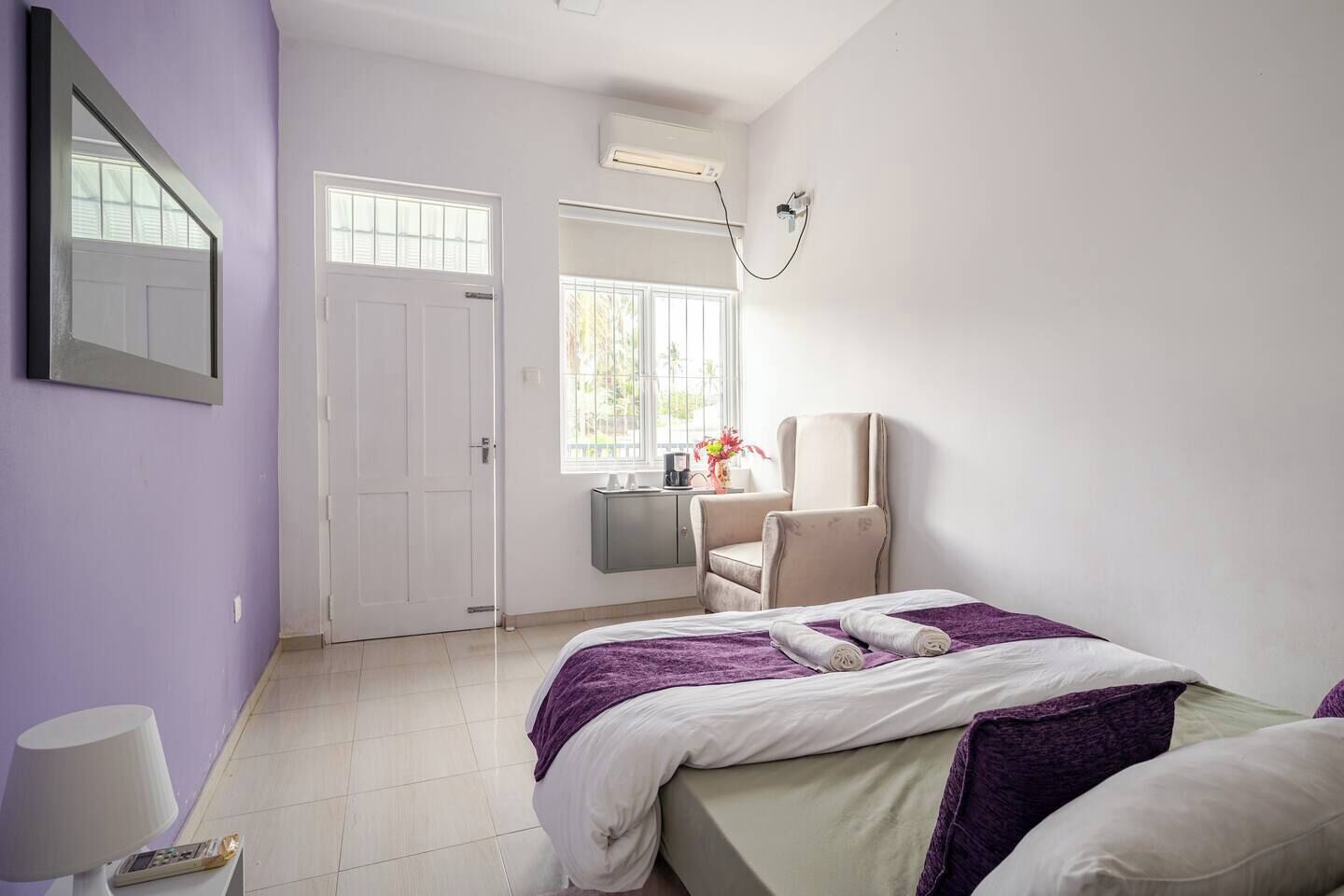 A hotel room with a bed, a chair, a desk, and a window.