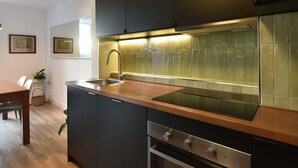 Una cocina moderna con muebles oscuros, un lavamanos de acero inoxidable y un horno empotrado.