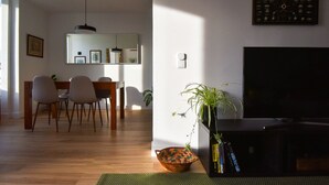 Una sala de estar con comedor, un televisor de pantalla plana y un reloj de pared.