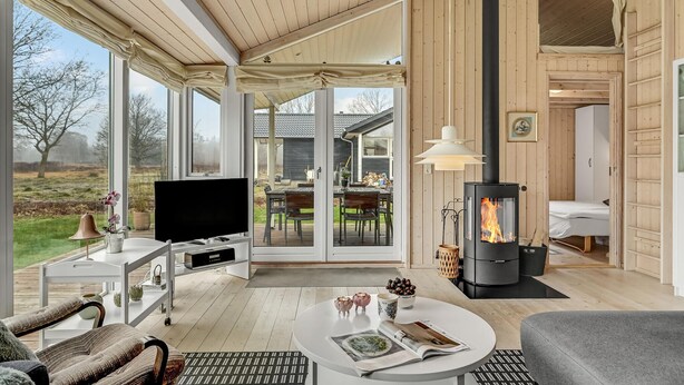 Una sala de estar acogedora con televisor grande, chimenea y comedor con vistas al exterior.