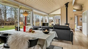 Una habitación acogedora y bien iluminada, con un ventanal grande, chimenea y una zona de estar confortable.