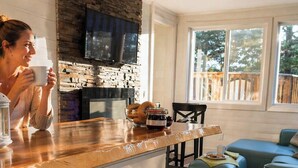 A kitchen with a stone backsplash, a built-in oven, and a dining area with blue upholstered seating. - del Sol - Private Hottub overlooking the 1000 Islands (Lansdowne)