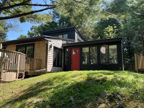 A modern house with a red door, large windows, and a wooden deck.