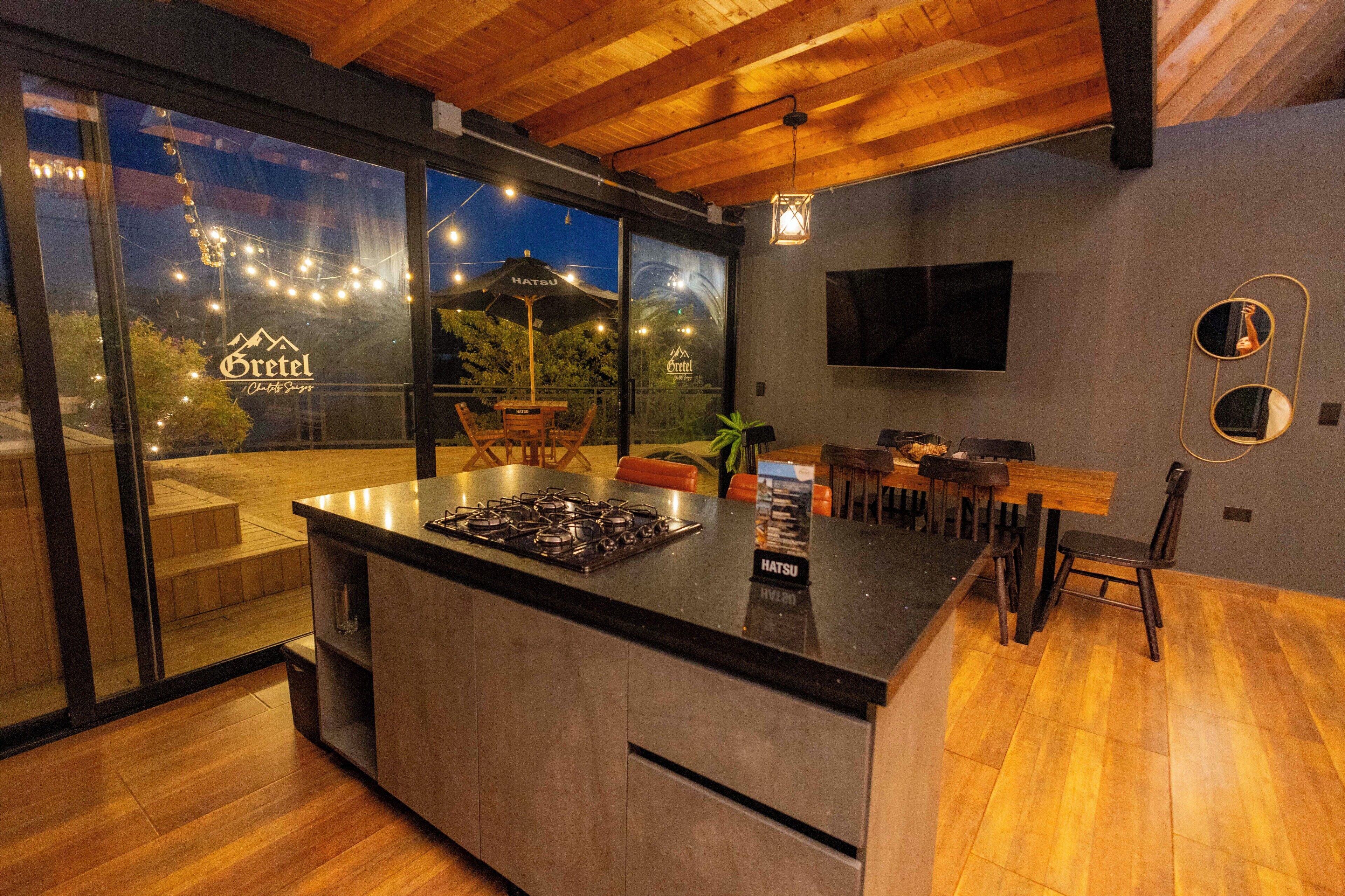 Una cocina moderna con una isla grande, techo de madera y vistas a través de puertas de cristal.