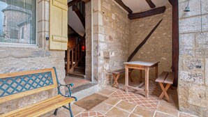 A rustic stone interior with a wooden bench, a small table, and a staircase leading to another room.