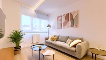 A modern living room with a sofa, two coffee tables, a floor lamp, and abstract wall art.