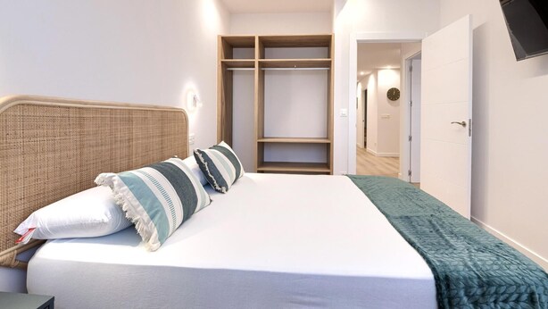 Une chambre à coucher comprenant un lit, une table de chevet, une armoire et un téléviseur fixé au mur.