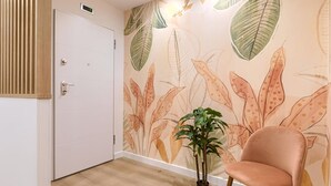 Une pièce avec une porte blanche, une plante en pot et une chaise rose.