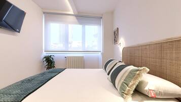 Een slaapkamer met een bed, een radiator, een raam en een plant.