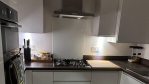 A modern kitchen with white cabinetry, a gas stove, and a built-in oven. - Luxurious Home Near Luton Airport. Suitable for Families and Contractors (Luton)