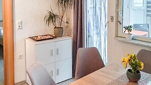 A dining area with a wooden table, two chairs, a potted plant, and a window with curtains. - 2 bedroom awesome apartment in Vir (Vir)