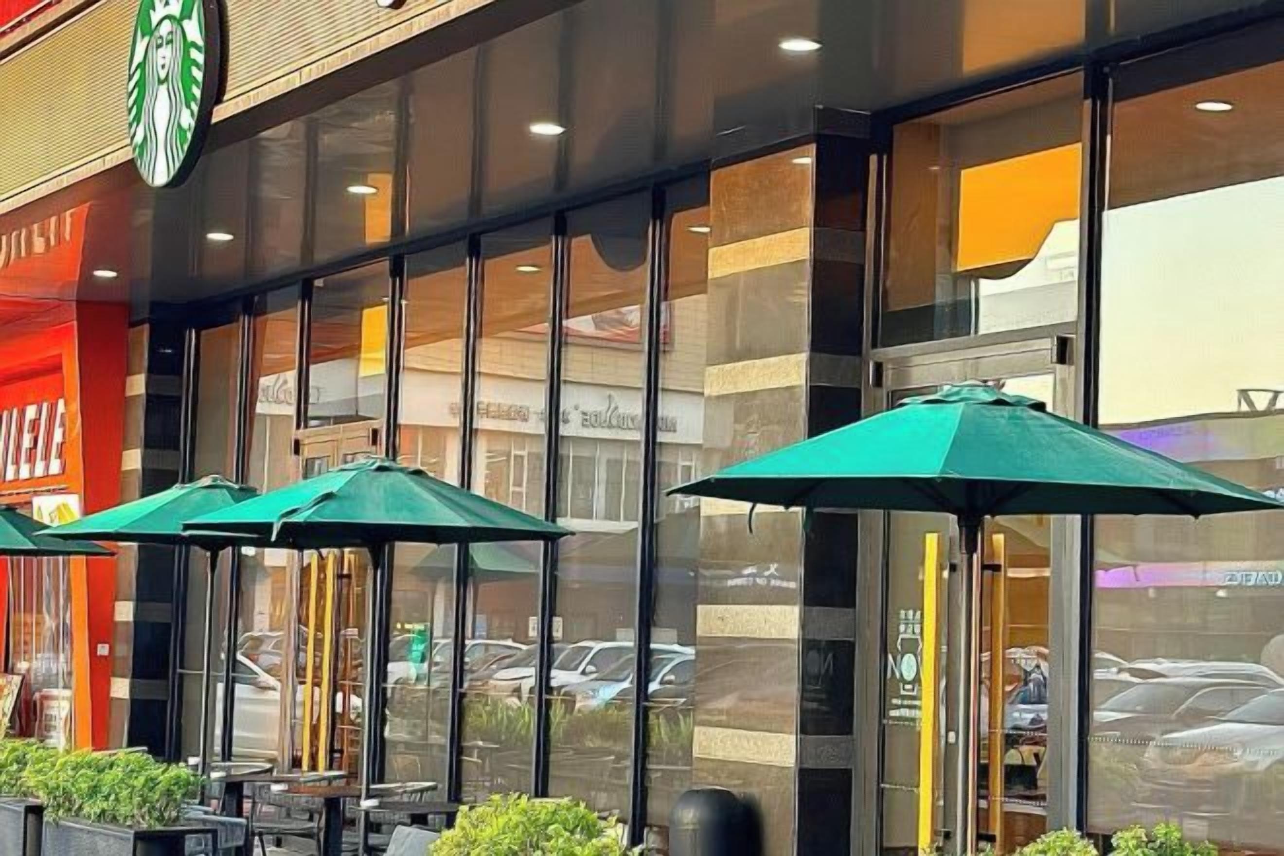 Ein Starbucks mit Außenbereich und Sonnenschirmen.