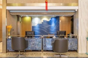 A reception desk with two black chairs, a marble counter, and a blue abstract wall art.
