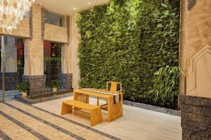 A lobby with a green vertical garden wall, a wooden bench, and a chandelier. - Lizhi Fengshang Hotel (Jingdezhen)
