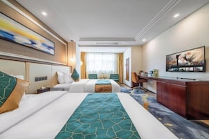 Habitación de hotel con dos camas, un escritorio y un cuadro grande en la pared.