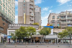 Un hotel con fachada moderna, una entrada destacada y un cielo despejado.