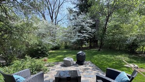 Une terrasse extérieure avec des meubles en osier, une table en pierre et un barbecue.