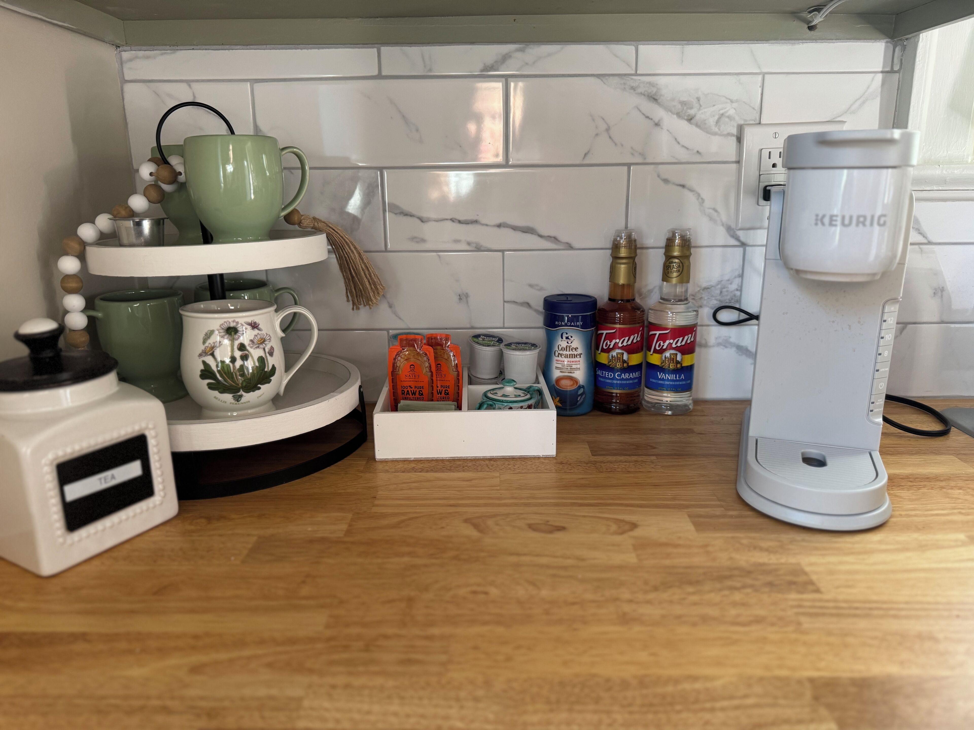 A kitchen counter with a coffee maker, tea kettle, and various coffee and tea products.