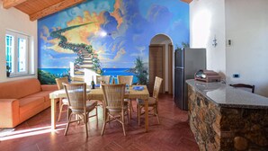 A dining area with wicker chairs, a wooden ceiling, and a mural of a staircase leading to a beach. - 4 bedroom lovely home in Ricadi (Ricadi)