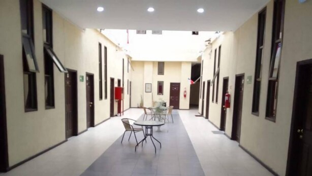 A hallway with a central table and chairs, flanked by doors and windows. - edificio catedral (Santiago)