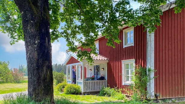 A red wooden house with a porch and a large tree in front. - 4 bedroom amazing home in Skillingaryd (Skillingaryd)