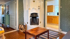 A cozy living room with a fireplace, wooden flooring, and a dining table. - 4 bedroom amazing home in Skillingaryd (Skillingaryd)
