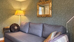 A room with a grey sofa, a decorative pillow, a lamp, and a mirror with an ornate frame. - 4 bedroom amazing home in Skillingaryd (Skillingaryd)