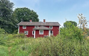 A red house with a tiled roof, surrounded by dense greenery and trees. - 4 bedroom amazing home in Skillingaryd (Skillingaryd)