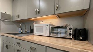 Eine Küche mit grauen Schränken, einer Mikrowelle, einem Toaster und einem Spülbecken.