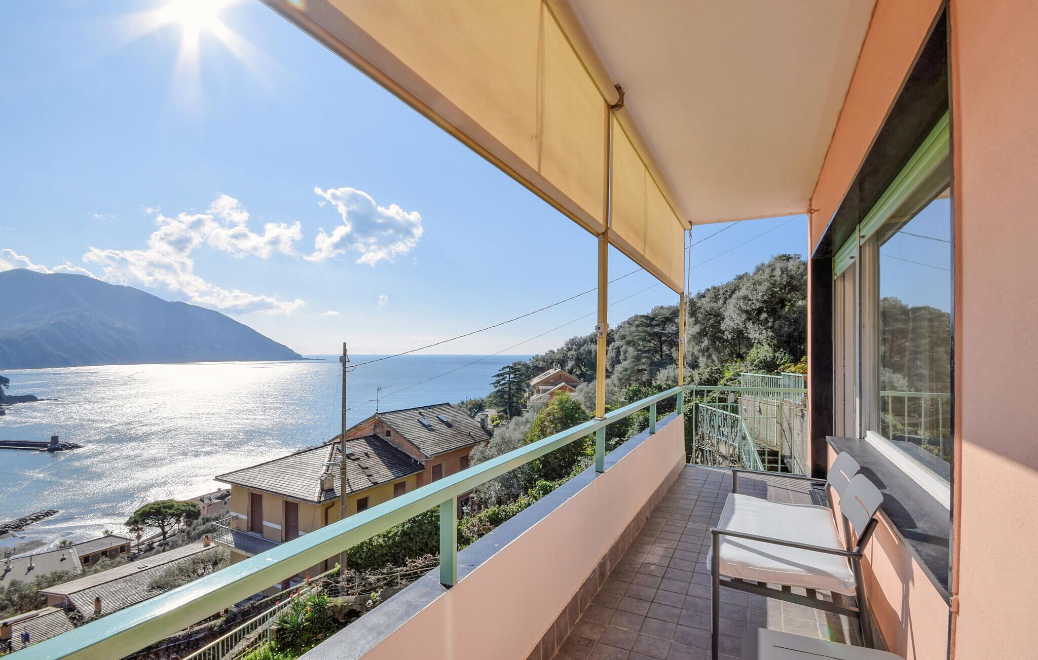 Uma varanda com vista para um lago e montanhas, piso de azulejos e corrimão.