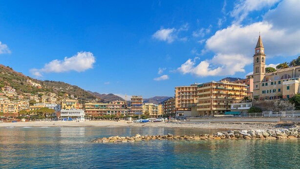 A coastal town with a prominent clock tower, terraced buildings, and a rocky shoreline. - Amazing apartment in Recco with WiFi (Recco)