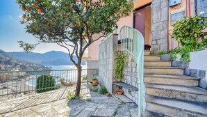 A stone staircase leading to a balcony overlooking a coastal view with a tree bearing fruit. - Amazing apartment in Recco with WiFi (Recco)