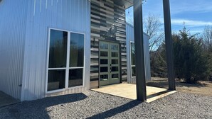 Een modern gebouw met een garagepoort, grote ramen en een overdekt buitengebied.