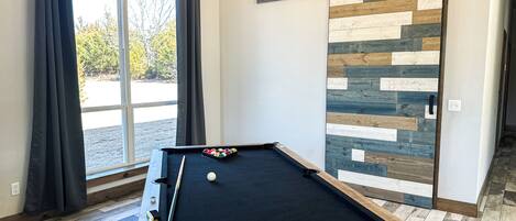 A pool table with a cue stick, billiard balls, and a chalk holder.