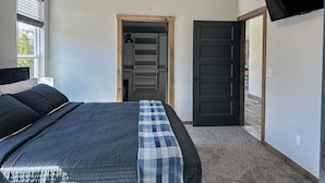 Een slaapkamer met een bed, een kast en een aan de muur bevestigde televisie.