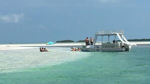A boat with a covered deck and a ladder, surrounded by clear turquoise water and a white sandy beach. - Sea Glass House of Summerland Key!
Pool, 70 feet of Seawall, deep water canal! (Summerland Key)