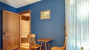 A room with a wooden door, two wooden chairs, a small table, a framed picture on the wall, and a window with sheer curtains. - Cobalt Suite at The Amethyst Inn B&B, jacuzzi, fireplace, gourmet breakfast (Adamstown)