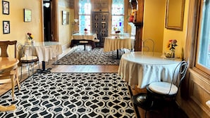 A dining area with a patterned floor, tables with white tablecloths, and chairs. - Cobalt Suite at The Amethyst Inn B&B, jacuzzi, fireplace, gourmet breakfast (Adamstown)