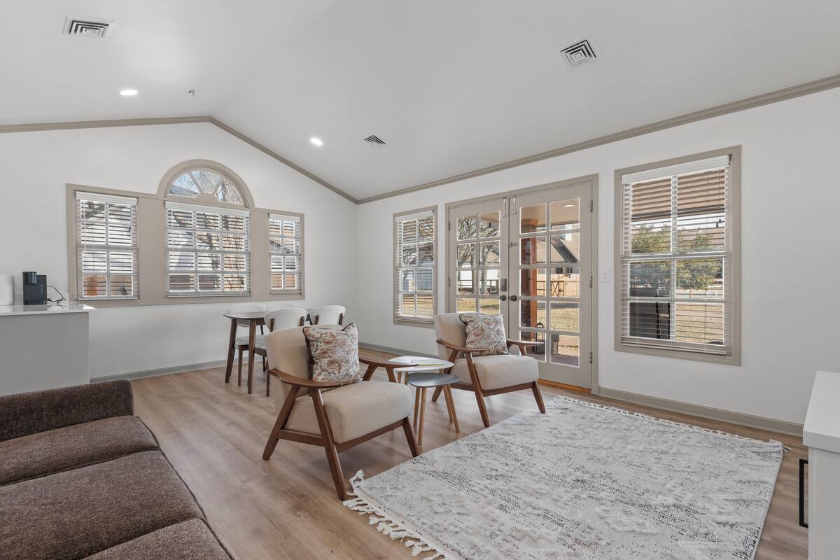 A spacious room with a large window, a cozy seating area with chairs and a rug, and a small table.