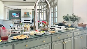Une cuisine spacieuse dotée d’un grand îlot central, d’appareils électroménagers modernes et d’une grande fenêtre.