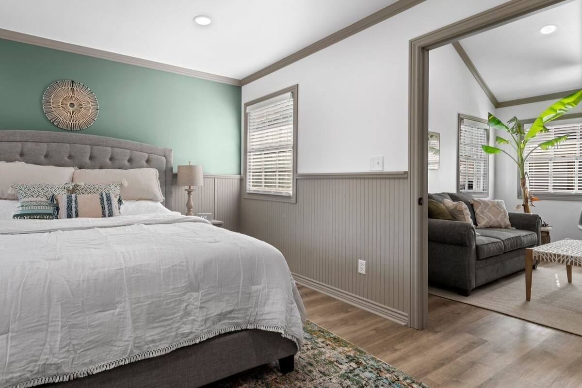 A bedroom with a large bed, a nightstand, a lamp, and a wall-mounted decorative item.