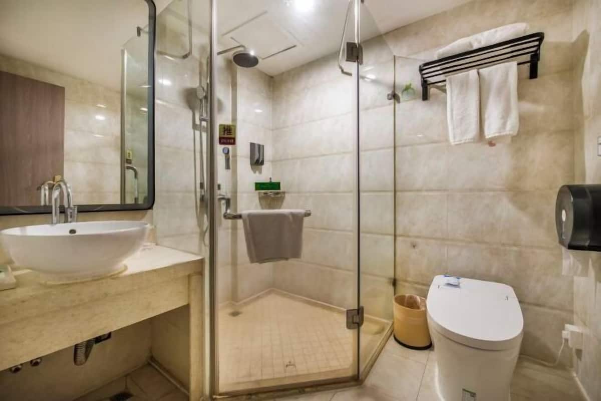 A bathroom with a glass-enclosed shower, a sink, a toilet, and a towel rack.