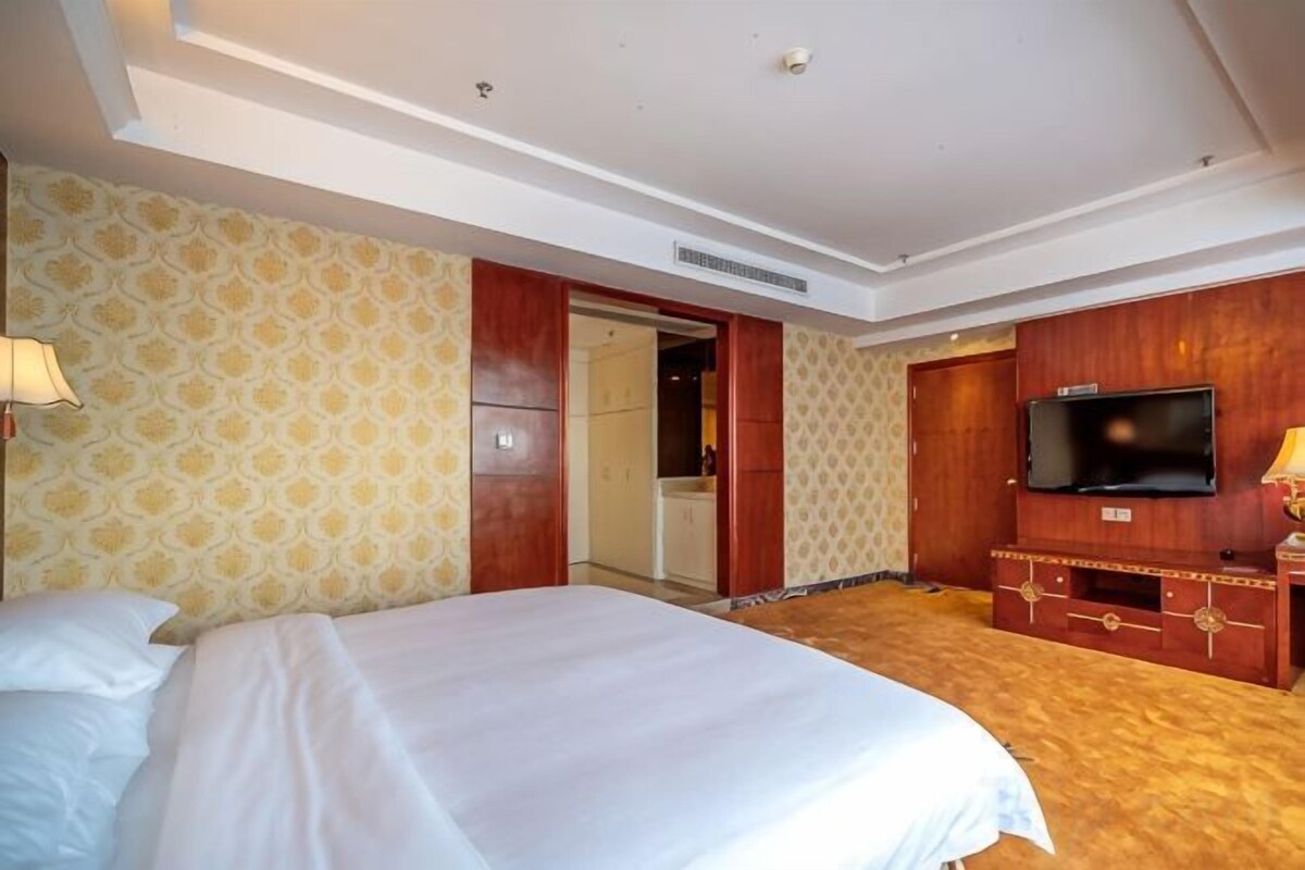 Une chambre d’hôtel avec un lit, une télévision, une armoire et une porte de salle de bain.