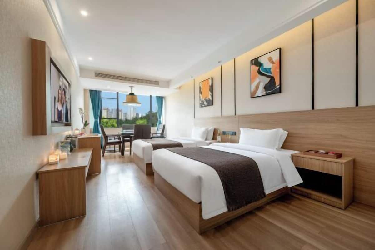 A modern hotel room with a large bed, a desk, and a view of the city.