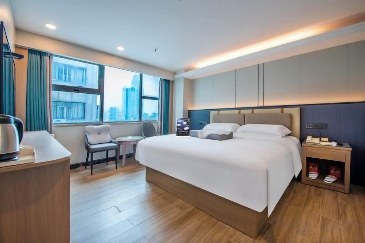 Une chambre d’hôtel avec un grand lit, un bureau, une chaise et une vue sur la ville.