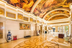 Un vaste hall d’entrée avec un plafond haut, des décorations somptueuses et un plancher poli.
