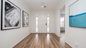 A hallway with wooden flooring, white walls, and framed artwork. - Rigby Retreat at St Leonards (St Leonards)
